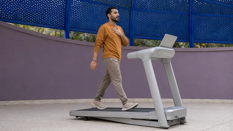 Beginner checking the incline setting during a steady treadmill walk