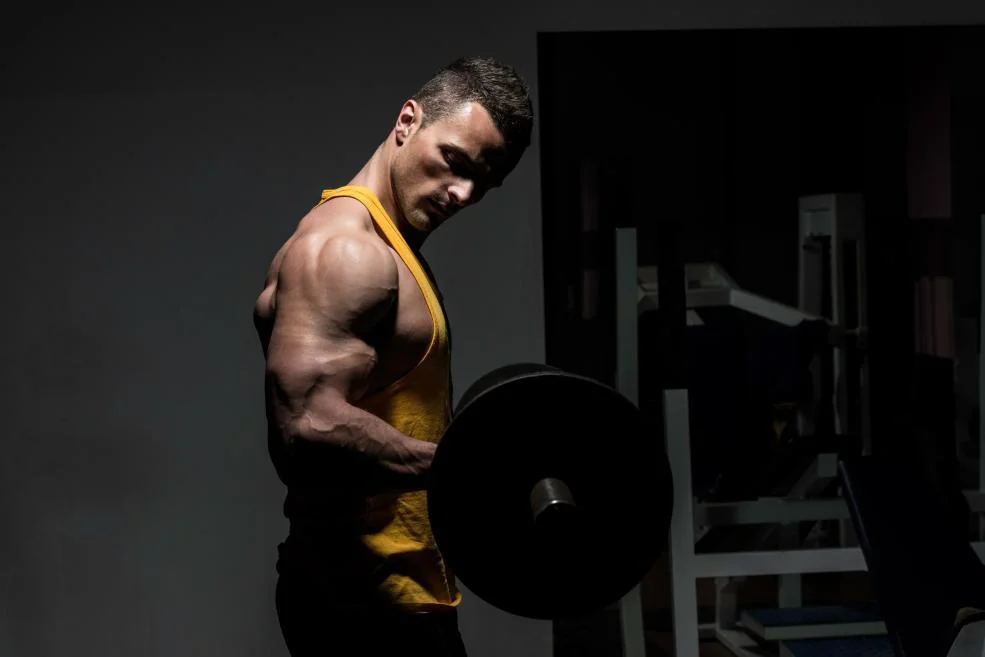 Mannelijke sporter gebruikt progressive overload met gewichten in de gym.
